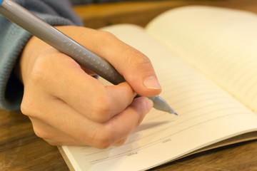 female hands with pen writing on notebook