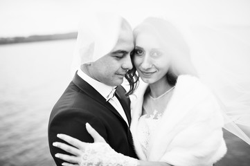 Close up wedding portrait of couple unde veil in cloudy weather