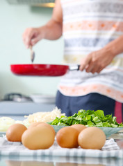 Lunch time! Man holding pan in the kitchen, eggs in the foreground