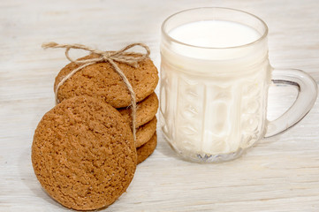 Fototapeta na wymiar Stack oatmeal cookies tied with thread with glass of milk