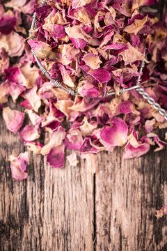 rose petals and dried flowers in spoon on old wooden table