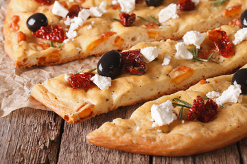 Sliced focaccia with dried tomatoes, feta and olives. macro horizontal
