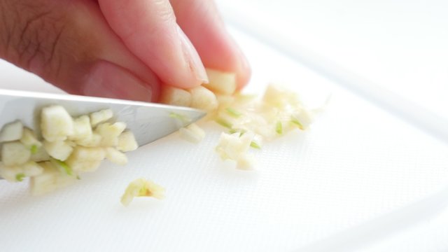 Cutting garlic onion vegetables on plate with knife 4K 2160p UltraHD footage - garlic onion cut on smaller pieces close-up 4K 3840X2160 UHD video 