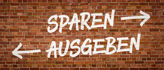 Schrift auf Backsteinmauer - Sparen oder Ausgeben