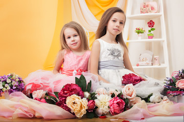 Obraz na płótnie Canvas Pretty twins posing with flowers in studio