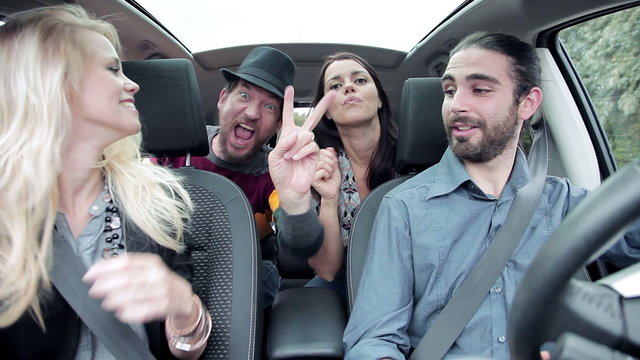 Cool people having fun laughing in car while taking selfie
