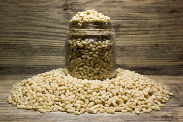 Grain of pearl Barley  and glass jar on a wooden background.