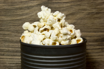 Popcorn in tin on wooden background