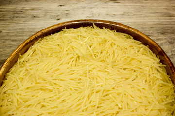 Small dry pasta noodles on wooden background