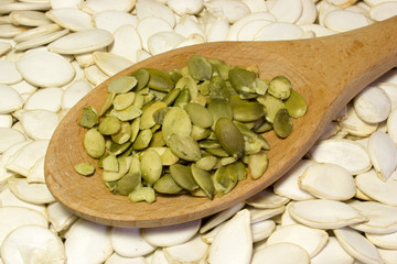 Pumpkin seeds and wooden spoon as background