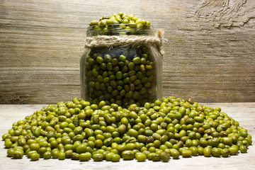 Green mung beans in glass jar on a wooden background