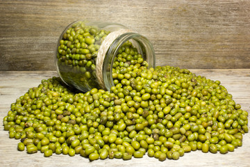 Green mung beans in glass jar on a wooden background