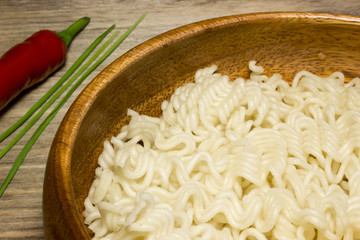 Instant noodles and red peppers on wooden background