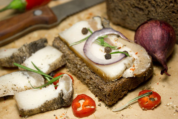 Slices of bacon with spices with rye bread. Kraft paper as the background.
