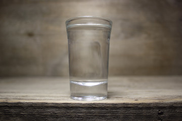 A glass of vodka on wooden table.