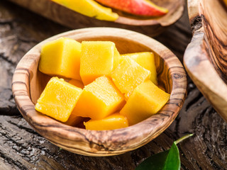 Pieces of mango fruit in the wooden bowl.
