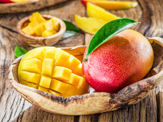 Mango fruit and mango cubes on the wooden table.