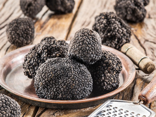 Black truffles on the plate on the old wooden table.