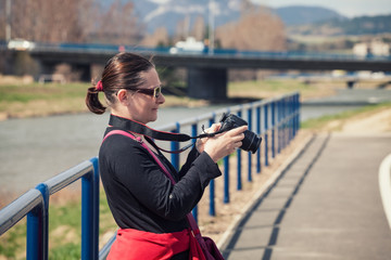 Portrait of female tourist holding camera and taking photos