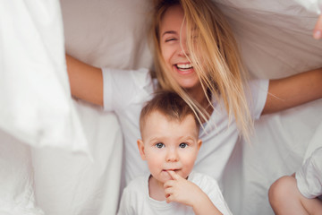 Fototapeta na wymiar Pretty child with smiling mother in bed in the morning