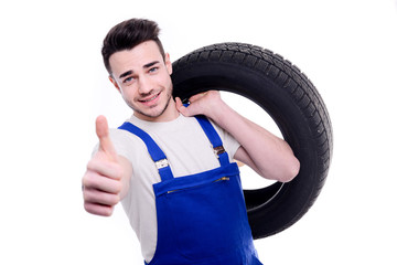 handsome young mechanic holding a tire isolated on white background
