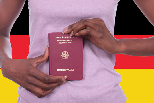 Afrikanische Frau mit deutschem Pass vor Deutschlandfahne