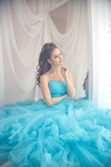 Beautiful young woman in gorgeous blue long dress like Cinderella with perfect make-up and hair...