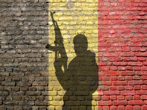 Shadow of man on Belgium flag painted brick wall