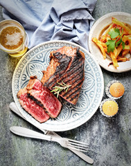 fried steak on a plate, chips, beer on a dark background
