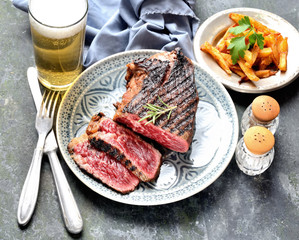 fried steak on a plate, chips, beer on a dark background