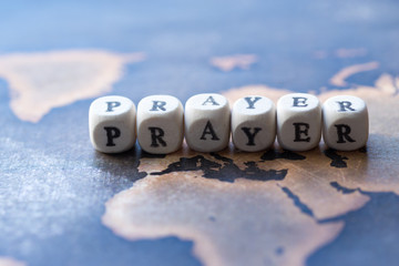 Wooden blocks with the text, Prayer, on the background of world map
