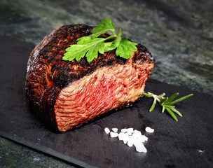 veal steak marbled basalt, a knife for meat, rosemary on a dark background