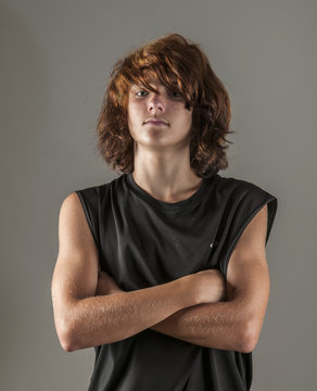 Handsome, strong teen boy in sleeveless shirt, arms crossed, looking cool