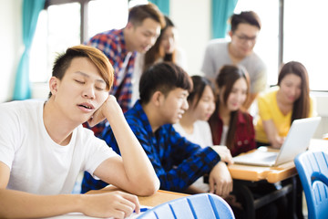 male Student sleeps on the desk in classroom