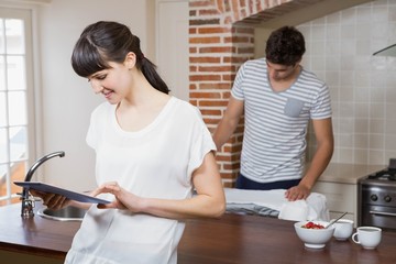Obraz na płótnie Canvas Woman using tablet in kitchen