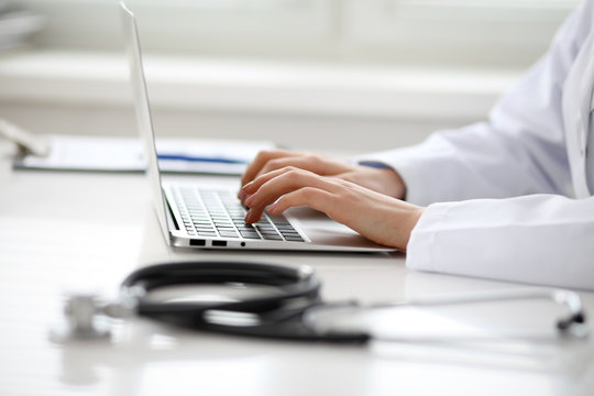 Female Doctor Typing On Laptop, Close Up