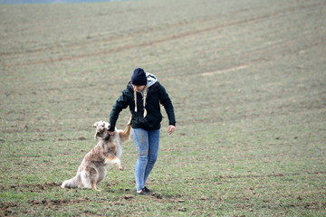 wer erzieht wen, junge Frau mit Zöpfen spielt mit Hütehund