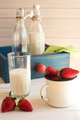 Fresh picked strawberrys with glass of the milk on white wooden background. Rustic style. 