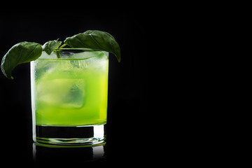 Summer cocktail with basil leaf isolated on black background