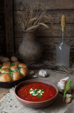 Traditional borscht Ukrainian or Russian beetroot soup with sour cream and garlic in clay dish on vintage wooden table background. Rustic style.
