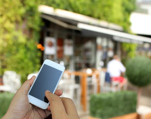 hand holding the smartphone on blur restaurant background