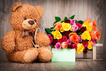 Roses and a teddy bear on wooden background