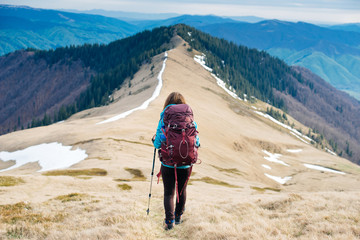 Girl tourist with backpack is traveling mountains