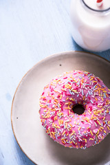 Vibrant pink donut with sprinkles and milk