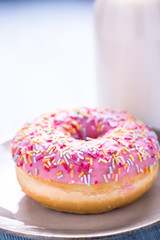 Vibrant pink donut with sprinkles and milk