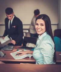 Multinational group of cheerful students taking an active part in a lesson while sitting in a lecture hall.