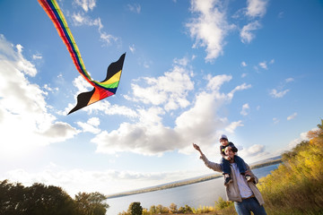 father with son in autumn playing with kite