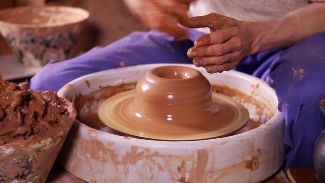 Hands of a potter creating an earthen jar on the circle
