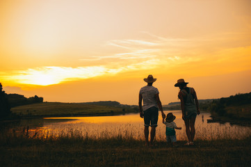 Happy family together, parents with their little child at sunset