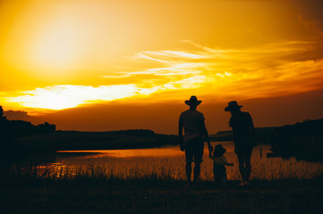 Happy family together, parents with their little child at sunset